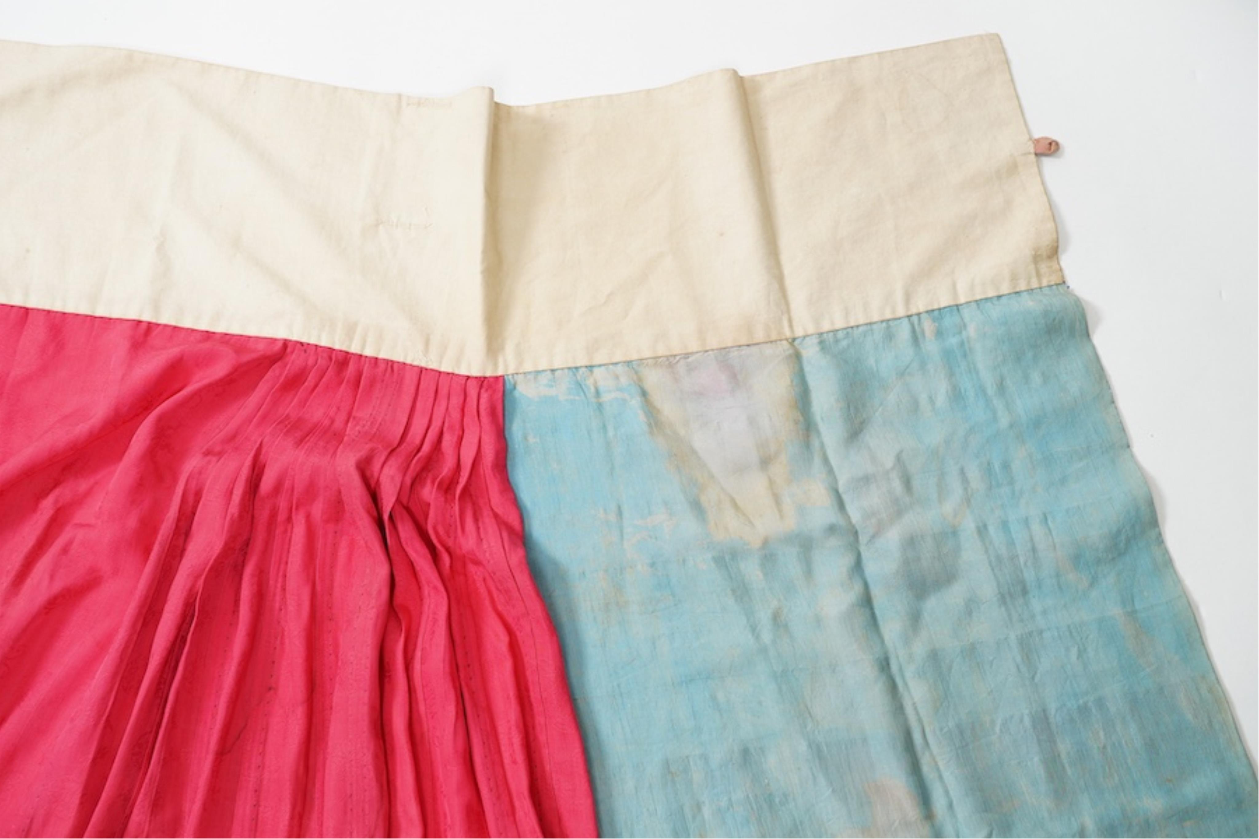 Two late 19th early 20th century Chinese wedding skirts. Made with pink silk damask, embroidered with large decorative silk floral and butterfly front panels bordered by blue embroidered black silk borders between pleats